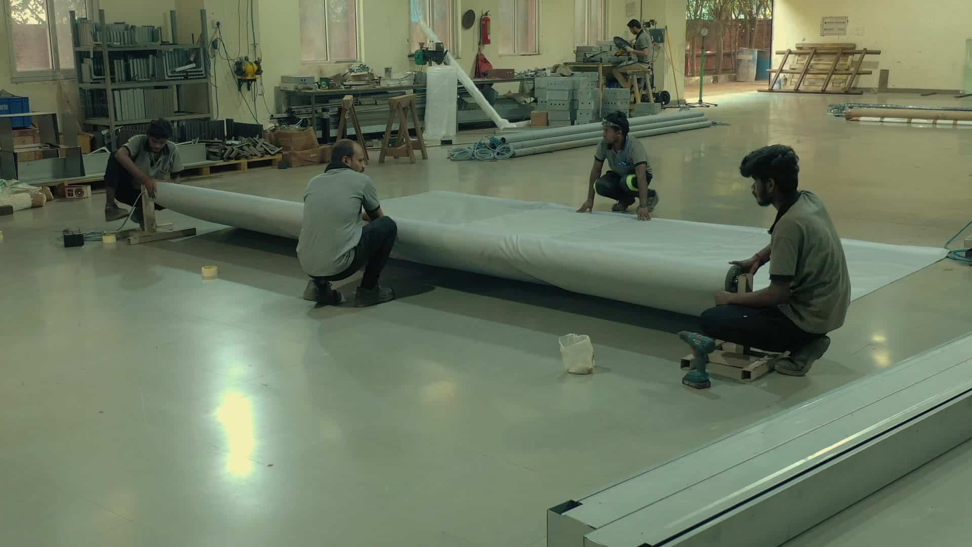 Plant staff laying out a long run of fire curtain fabric on the Jaipur plant floor